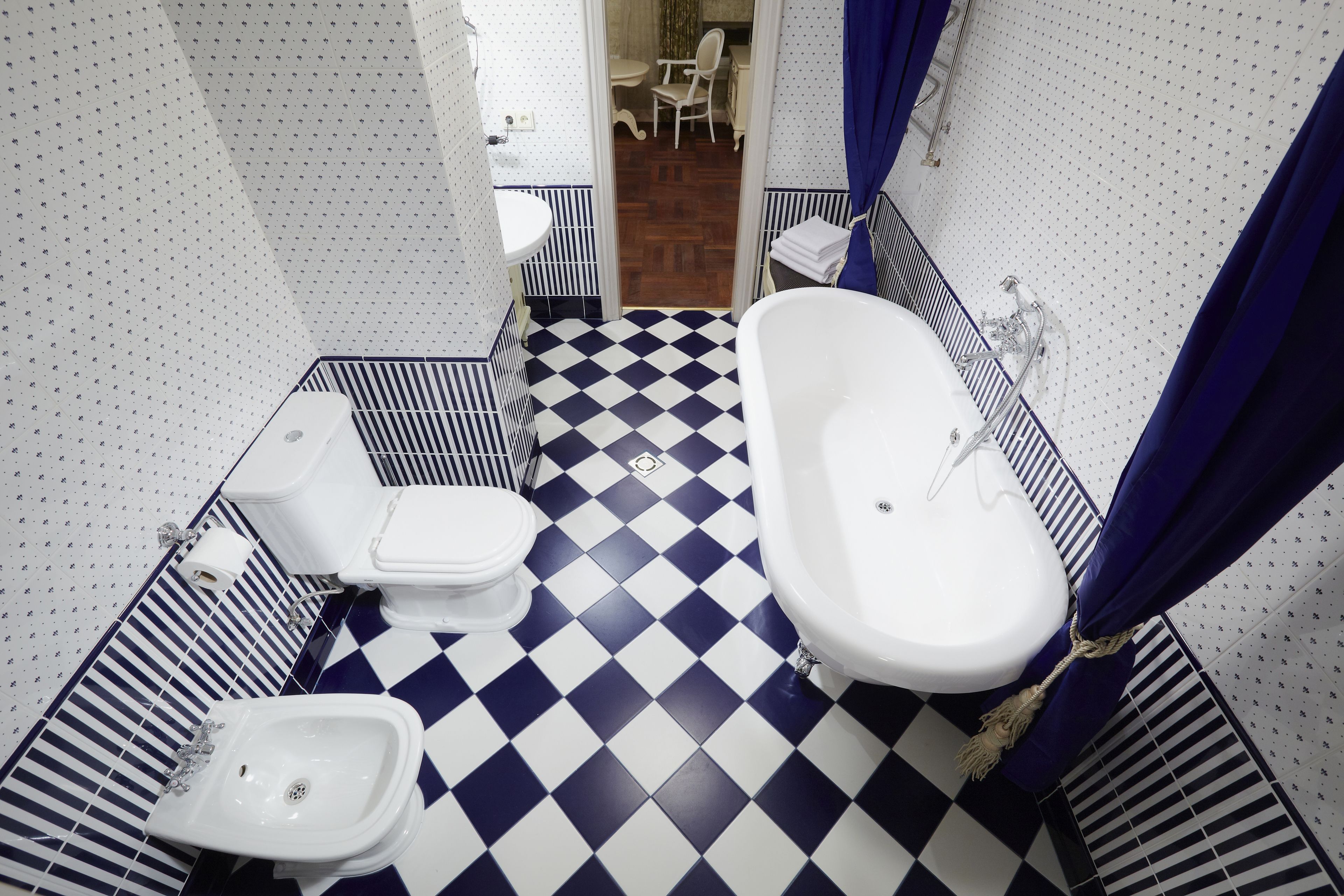 Une salle de bain avec un carrelage à motifs géométriques, des toilettes, un bidet et une baignoire.