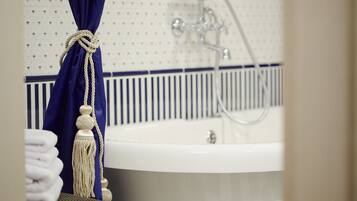 A bathroom with a white sink, a blue curtain tied with a rope, and a towel rack with folded towels.
