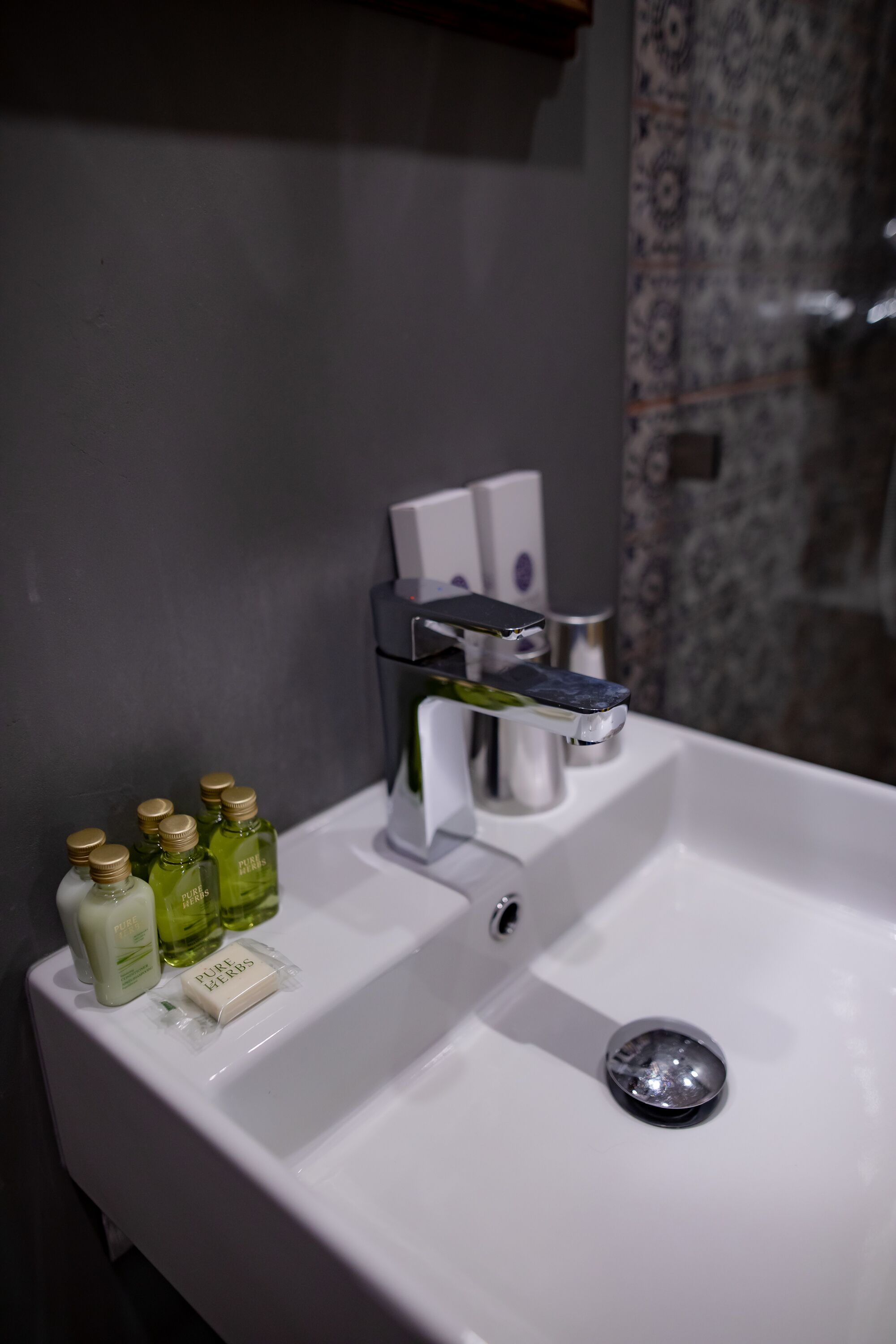 A bathroom sink with a modern faucet, a soap dish, and several bottles of liquid soap.