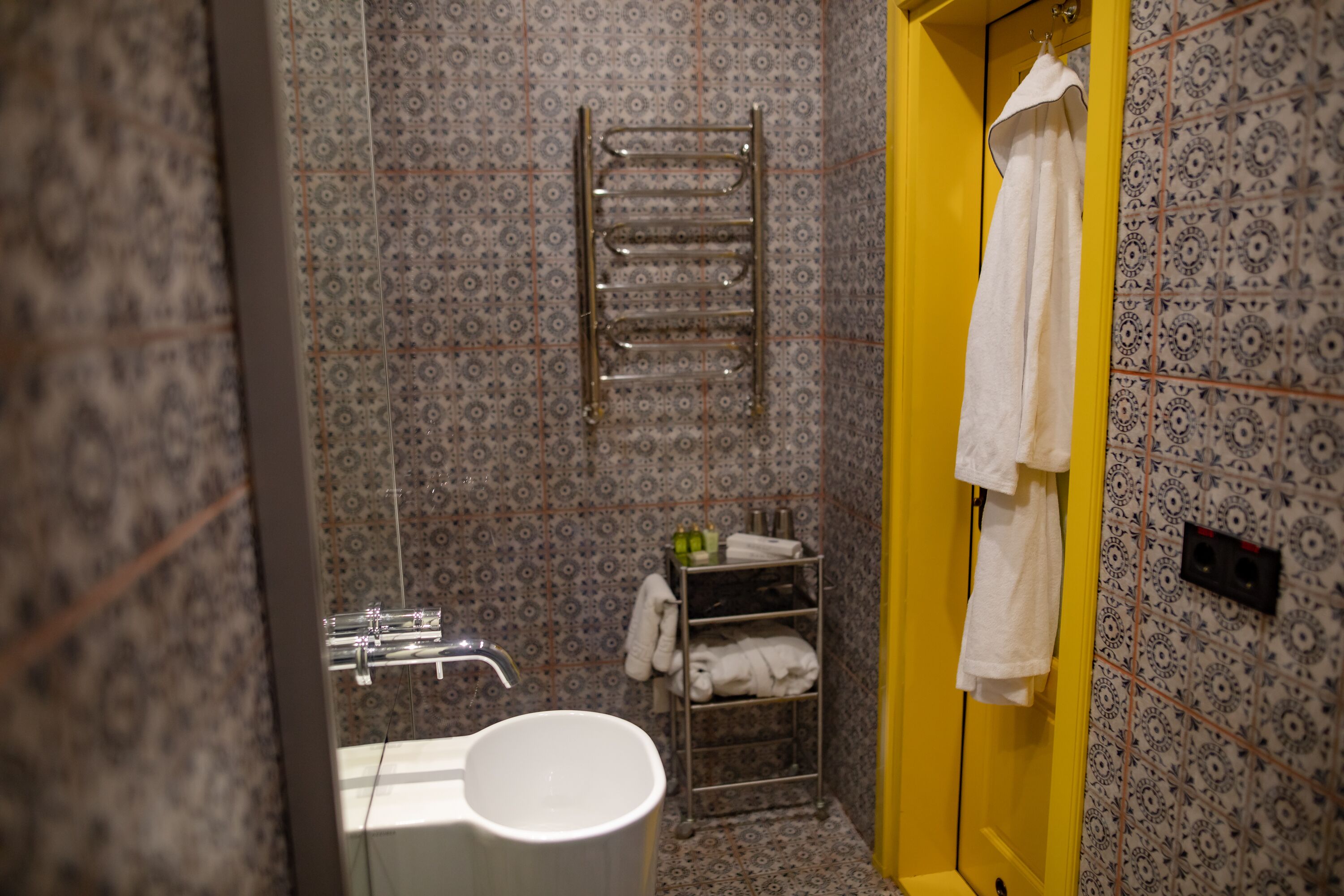 A bathroom with a white bathtub, a towel rack, and a shelf with towels.
