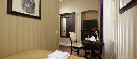 A hotel room with a bed, a desk with a chair, a television, and a mirror.