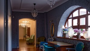 Ein geräumiger Raum mit Holzboden, einem Essbereich mit Tisch und Stühlen, einer Kandelaber und einem großen Bogenfenster mit Blumen.