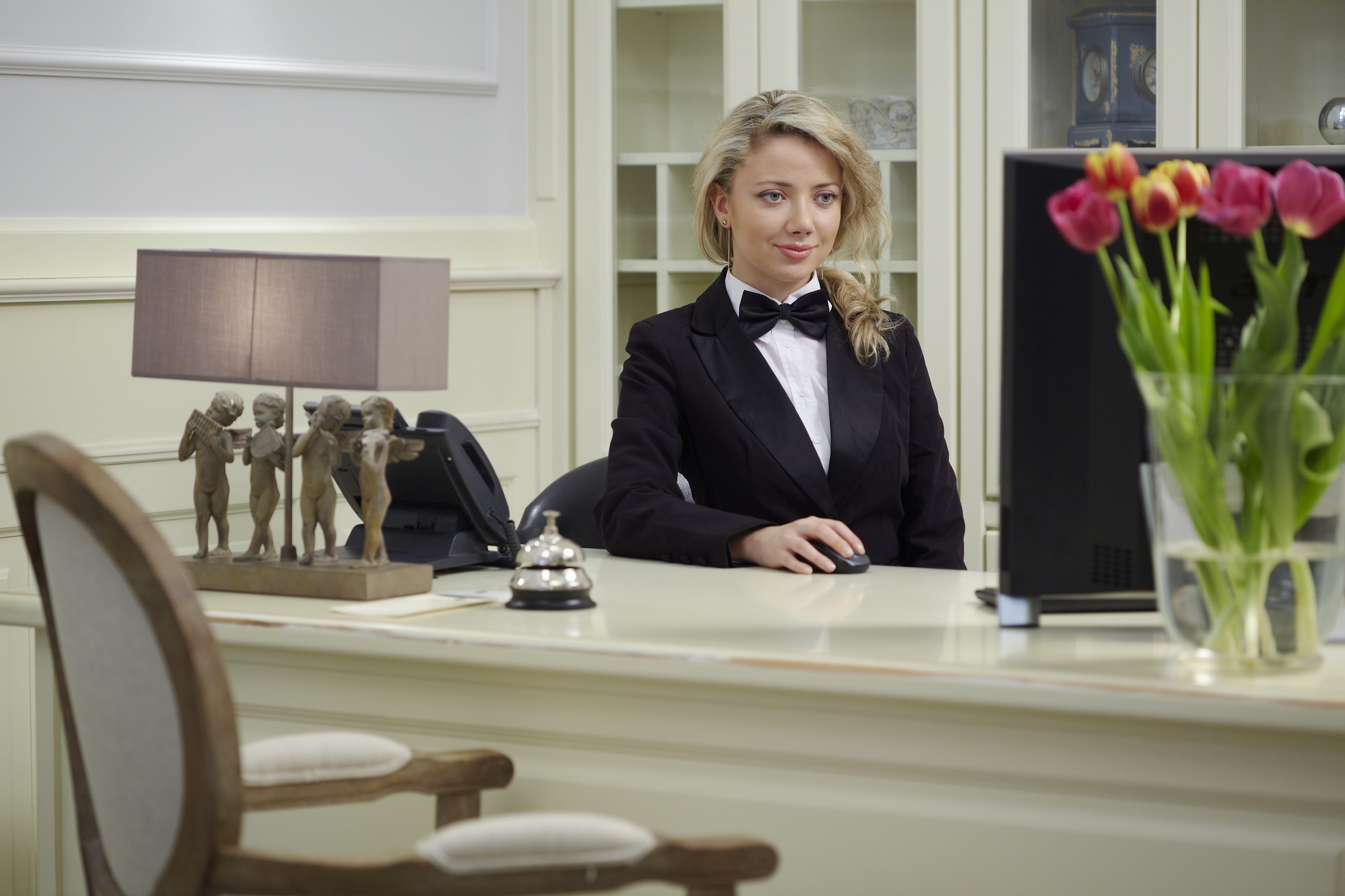 Een receptiebalie met een telefoon, een lamp en een vaas met bloemen.