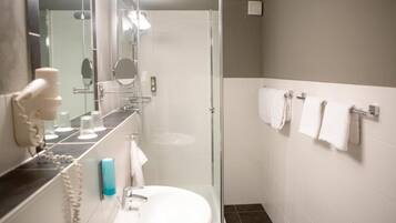 Un baño moderno con ducha envuelta en vidrio, un lavamanos blanco y un espejo.