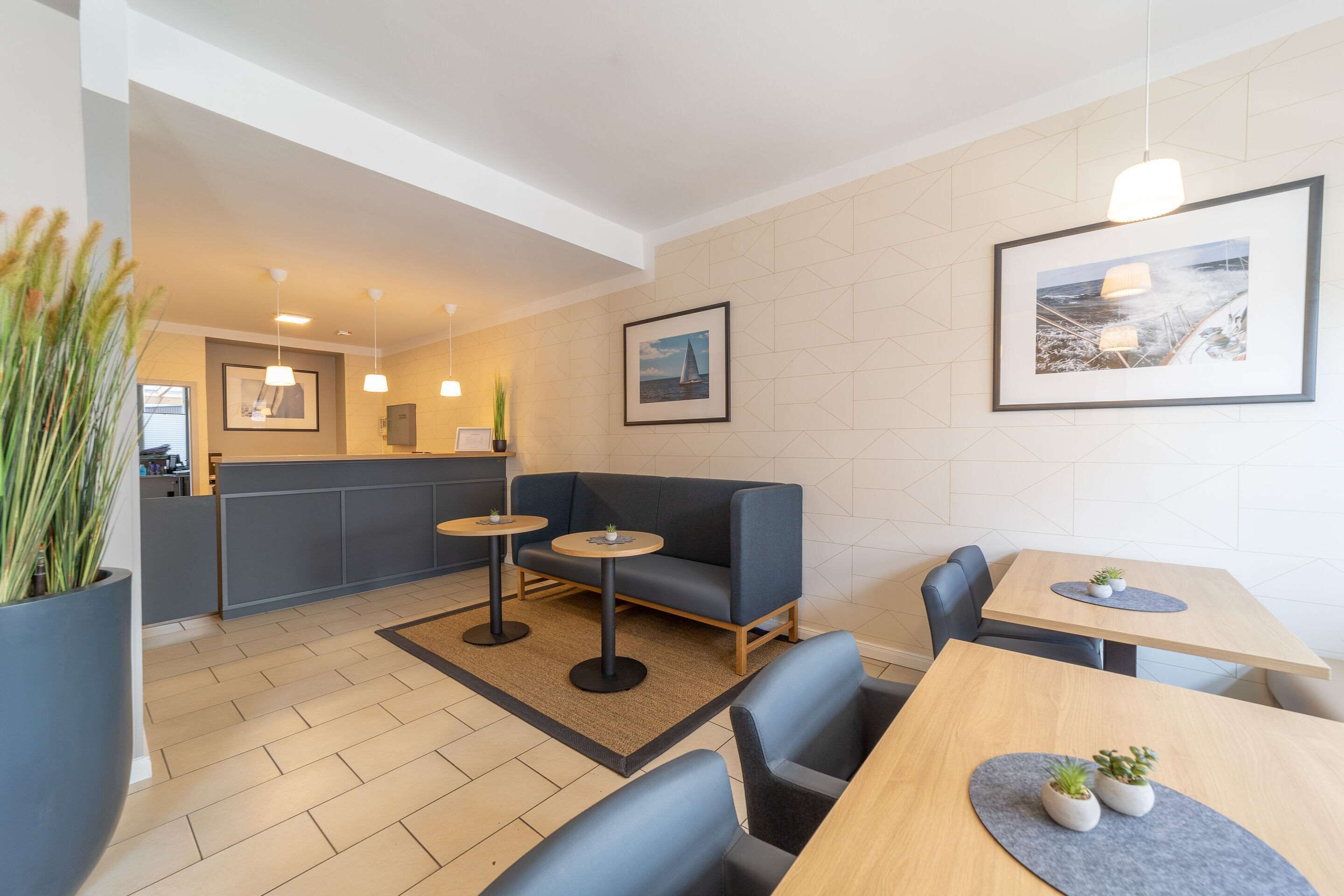 Un intérieur moderne avec un canapé, deux petites tables, une table en bois et une grande plante en pot.