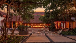 A traditional building with a tiled roof, a bar area with seating, and a well-maintained garden with pathways and seating arrangements. - Alila Diwa Goa - A Hyatt Brand (Majorda)
