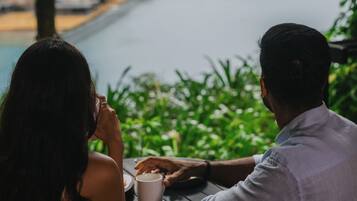 Two people sitting at a table with a view of a pool and greenery.