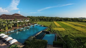 Relax by the resort's large pool surrounded by lush greenery and palm trees.
