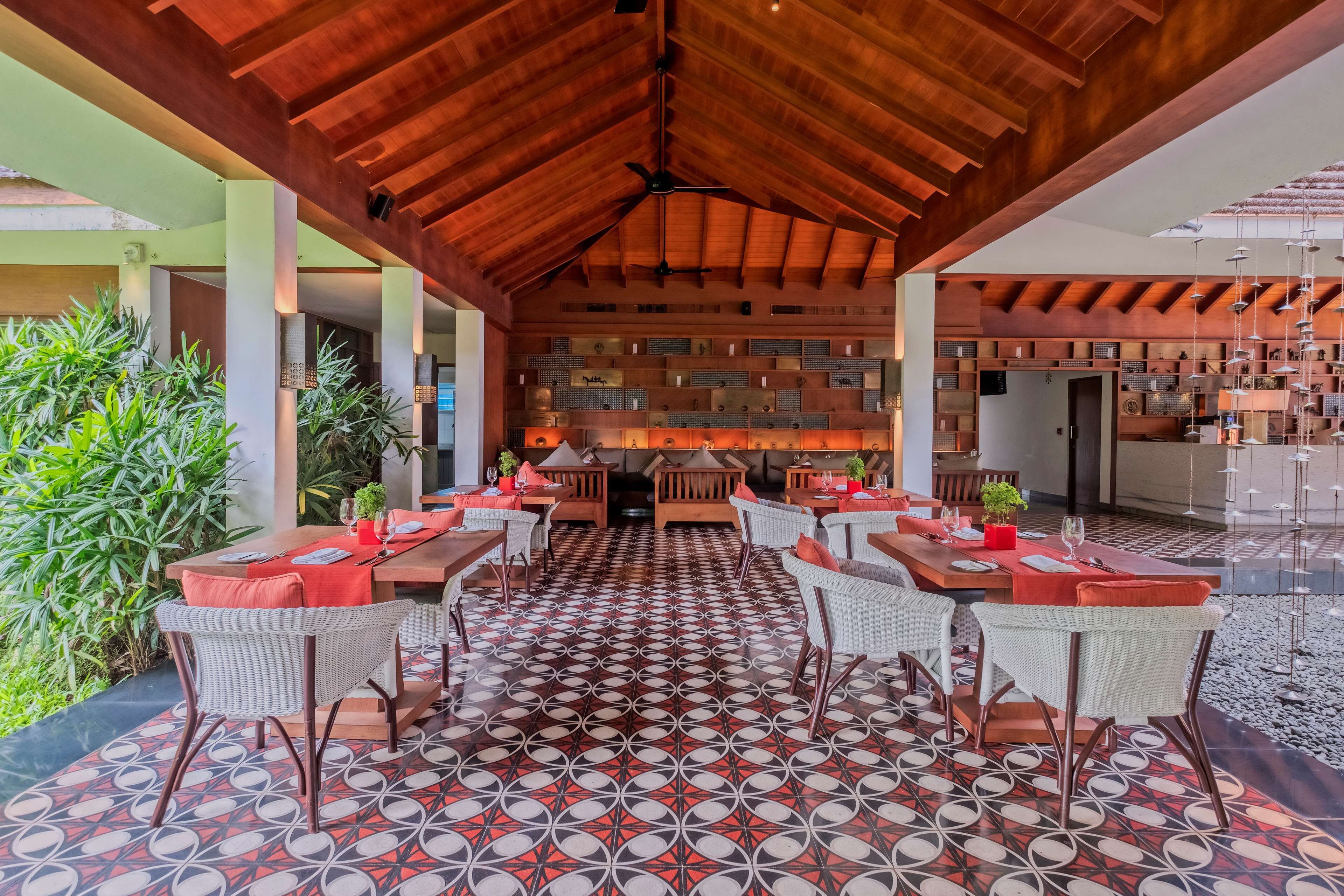 An indoor dining area with a patterned floor, wooden ceiling beams, and a variety of seating arrangements.