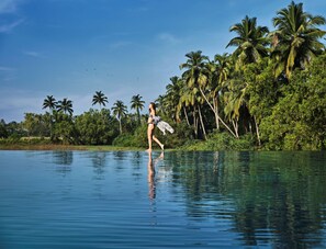 A woman in a bikini walking on a beach with palm trees and a clear sky.