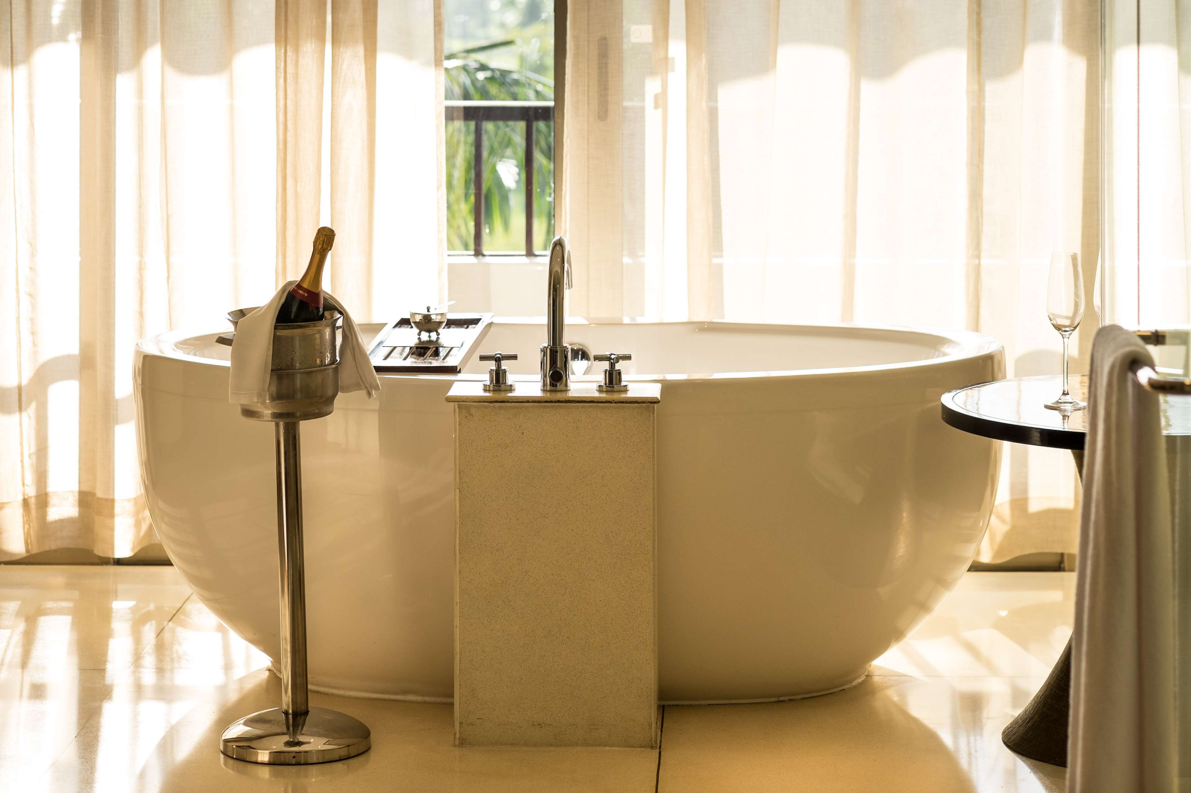 A modern bathroom with a freestanding bathtub, a sink, and a glass of champagne.