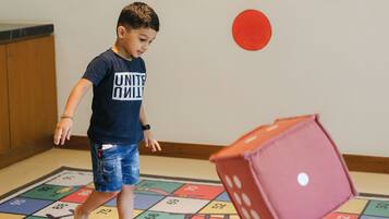 A child playing with a dice on a colorful board game mat.
