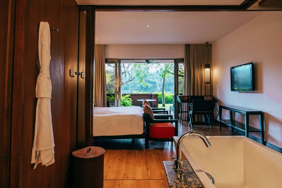 Een hotelkamer met een groot bed, een zithoek, een badkuip en een televisie aan de muur.