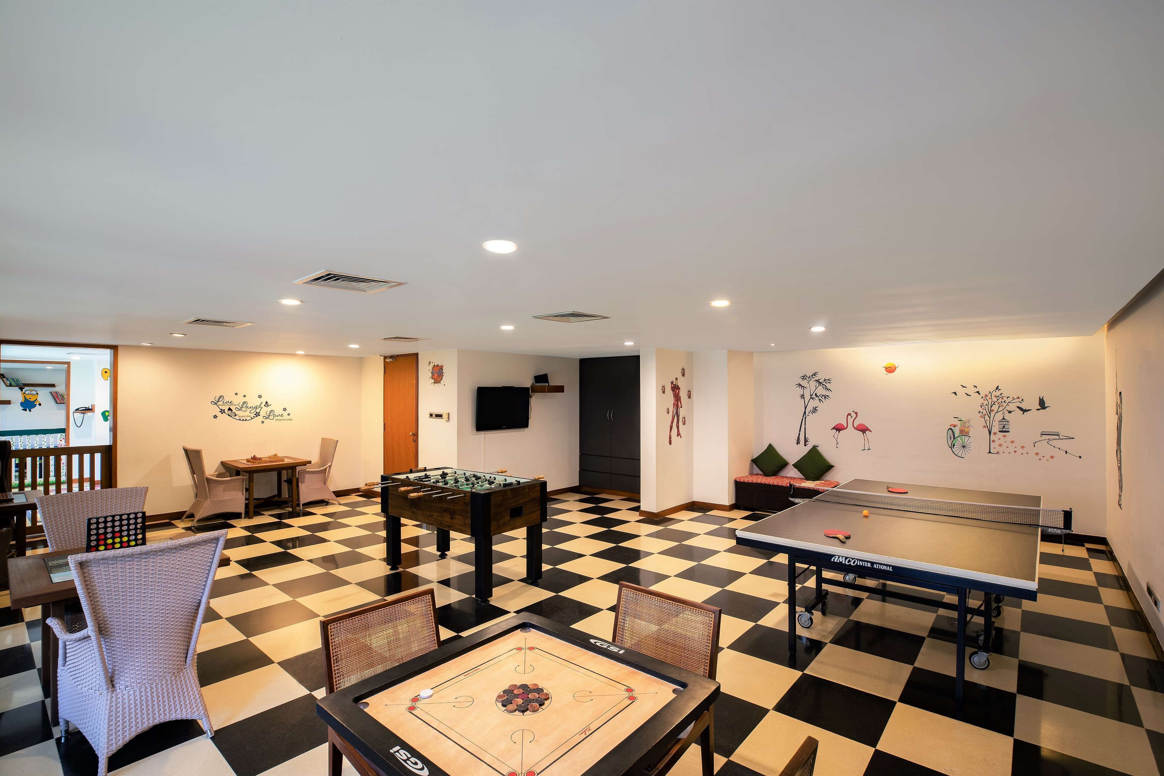 A room with a foosball table, ping pong table, and a checkered floor.