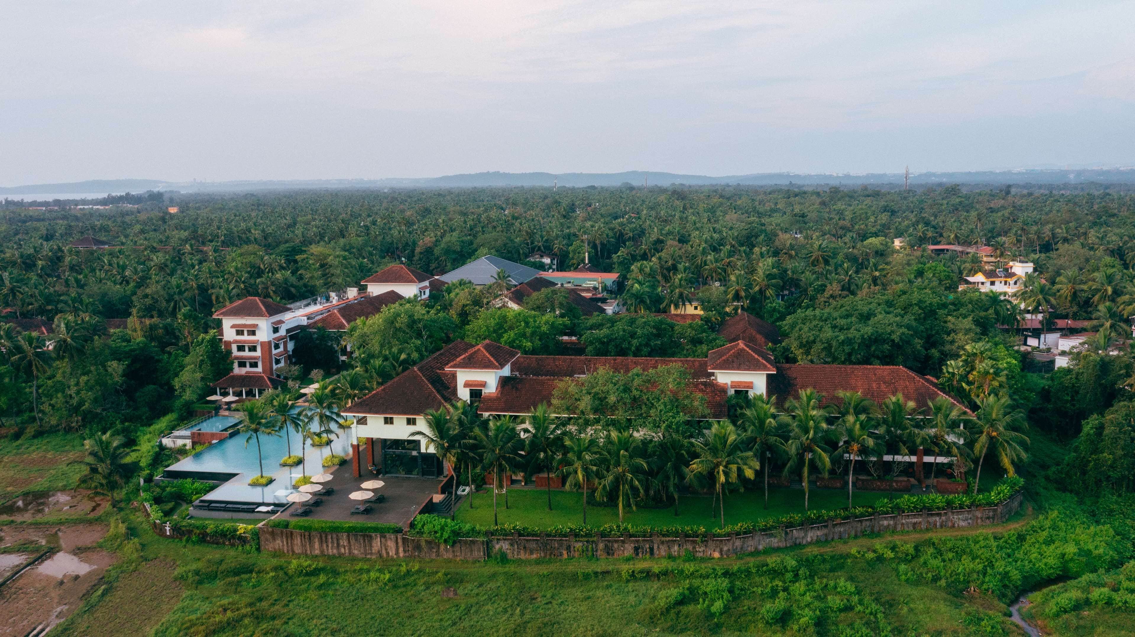 A resort with multiple buildings, a swimming pool, and lush greenery.