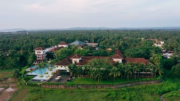 A resort with multiple buildings, a swimming pool, and lush greenery.