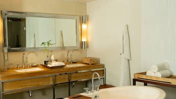 Un baño moderno con una bañera independiente grande, lavamanos dobles y un espejo amplio.