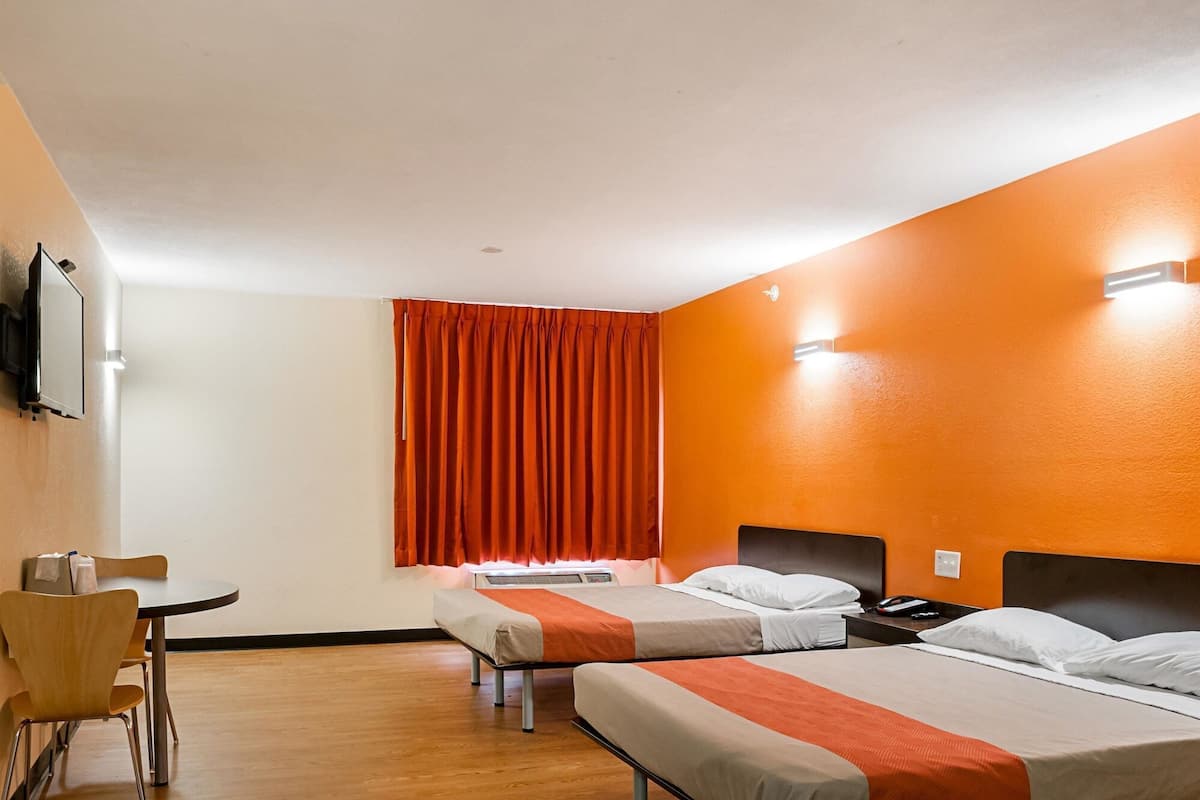 Una habitación de hotel con dos camas, un escritorio y una silla.