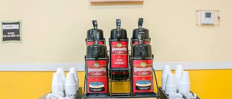 A coffee station with multiple coffee dispensers, cups, and a sign indicating it is family-owned since 1919.