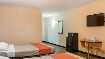 Habitación de hotel con dos camas, un escritorio, una silla, un televisor y un microondas.