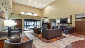 A spacious lobby with leather seating, a fireplace, and a television.
