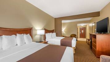 A hotel room with two beds, a television, a desk, and a chair.