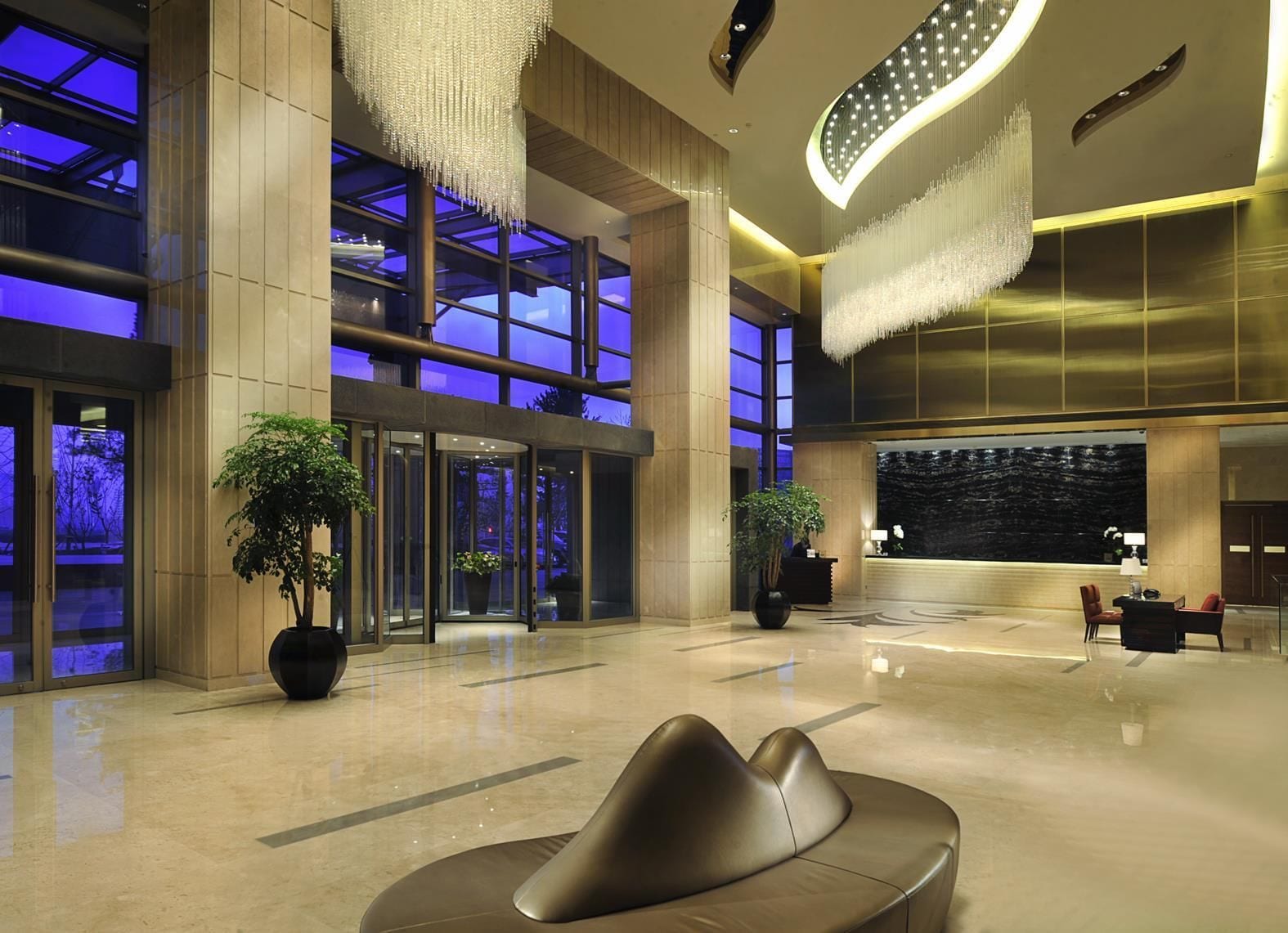 A spacious lobby with a modern design, featuring a reception desk, seating area, and large windows.