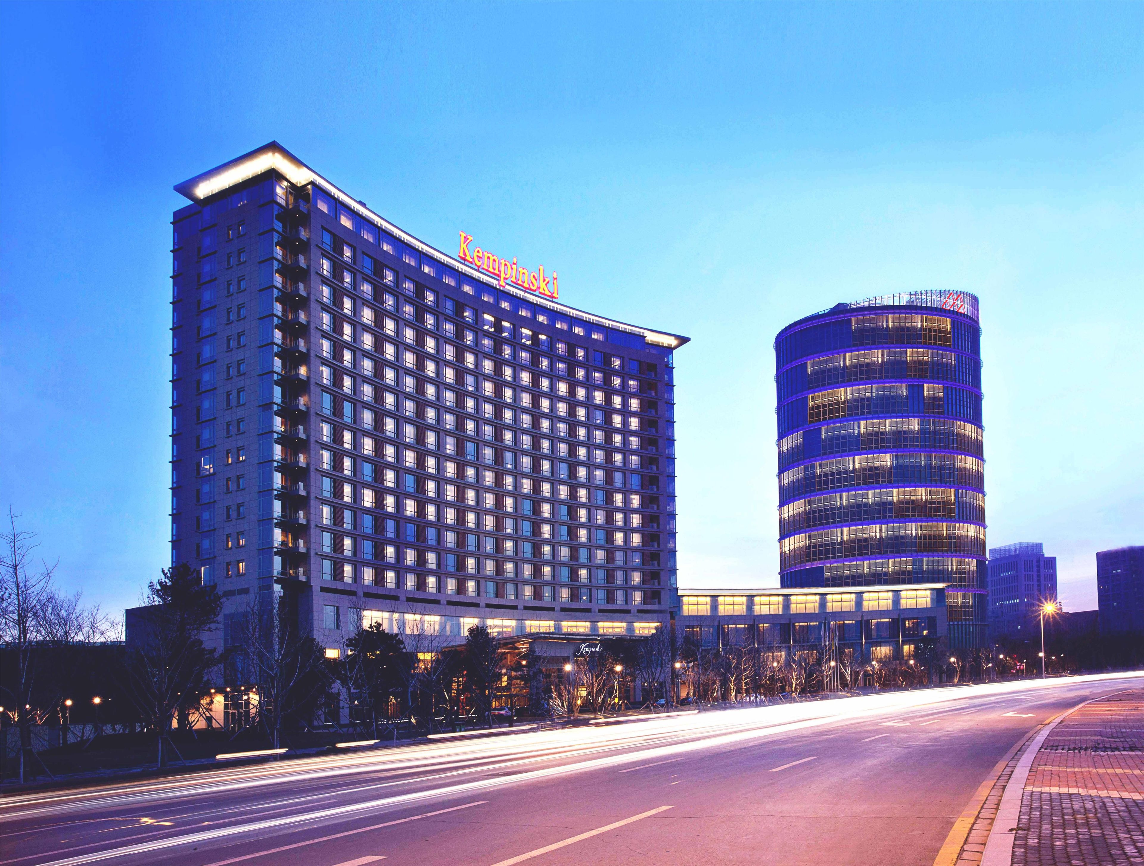 Un hotel de diseño moderno, con una fachada curva destacada y un edificio cilíndrico adyacente.