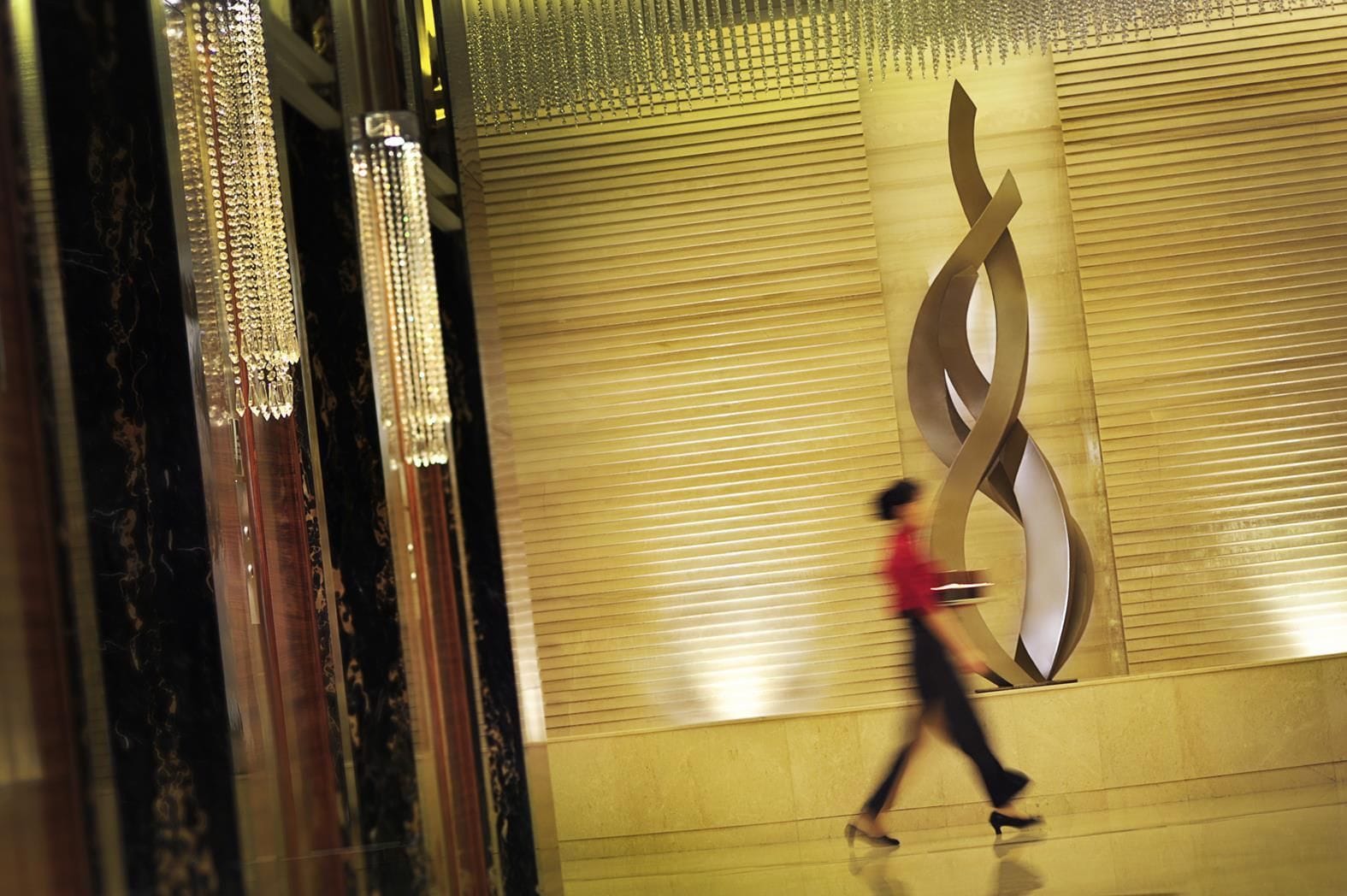 A person walking past a wall with a large, abstract design.