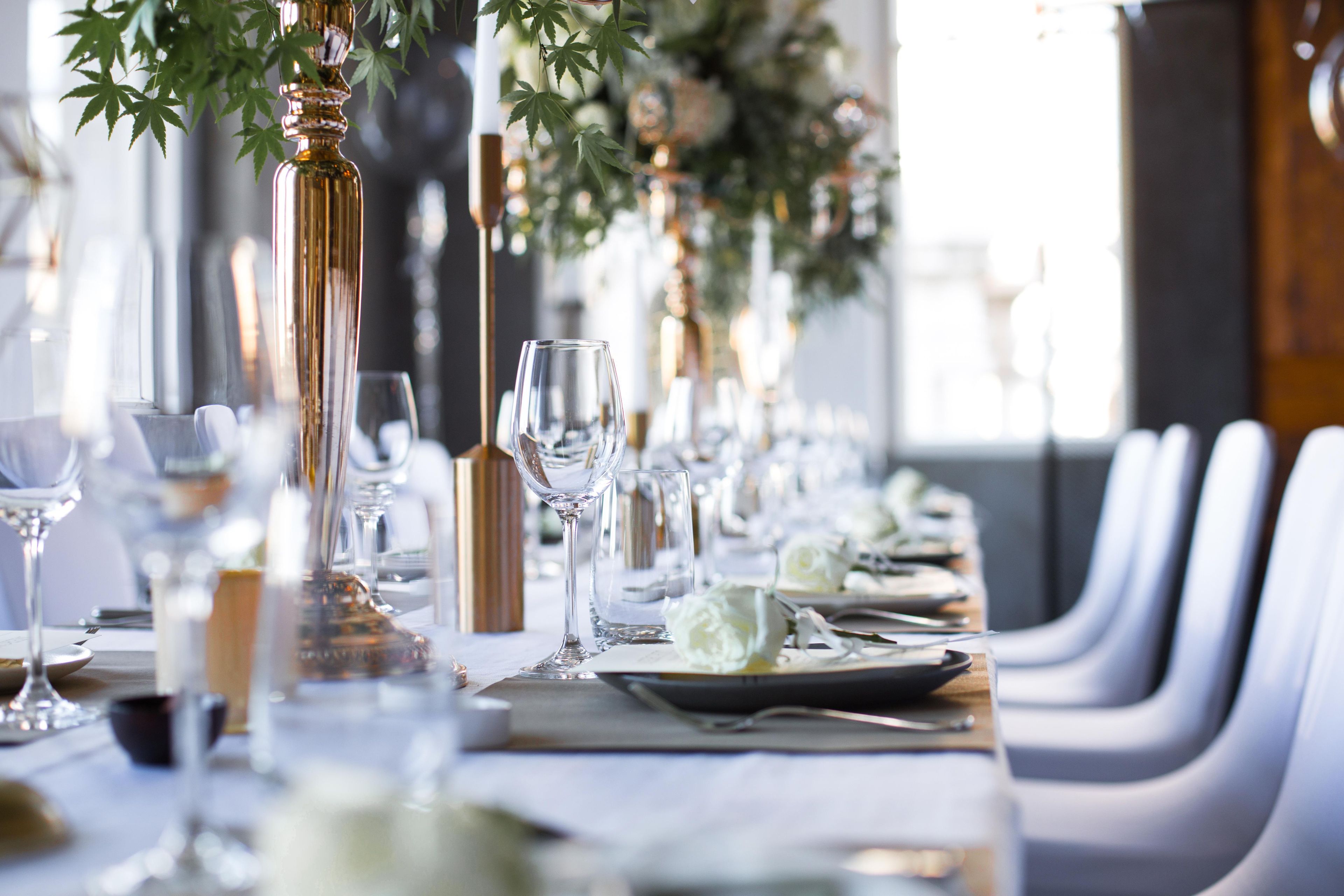 Une longue table à manger, entourée de chaises, mise avec des assiettes, des verres et des couverts.