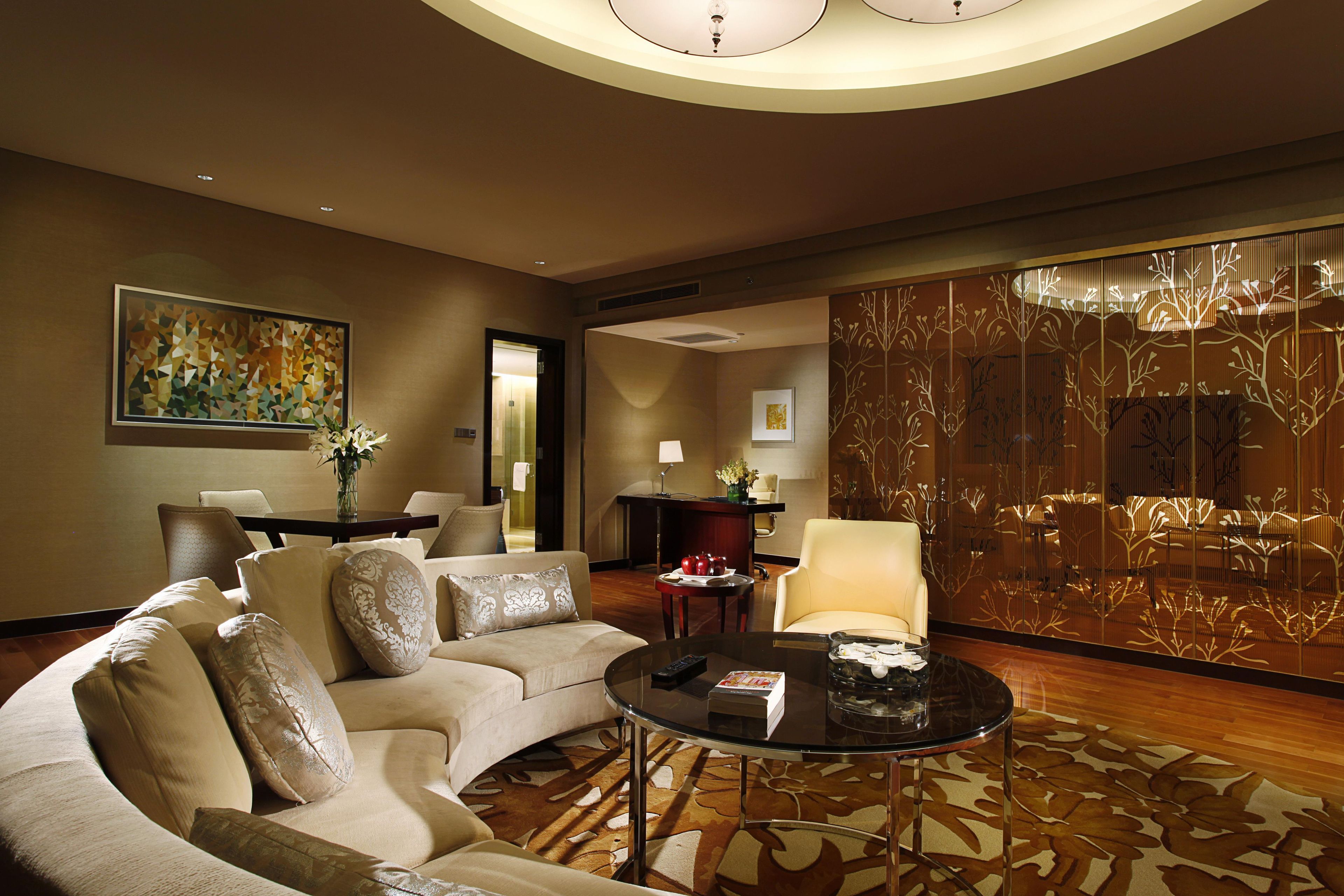 Une chambre d’hôtel moderne, dotée d’un canapé, d’une table basse ronde en verre et d’un panneau décoratif mural.