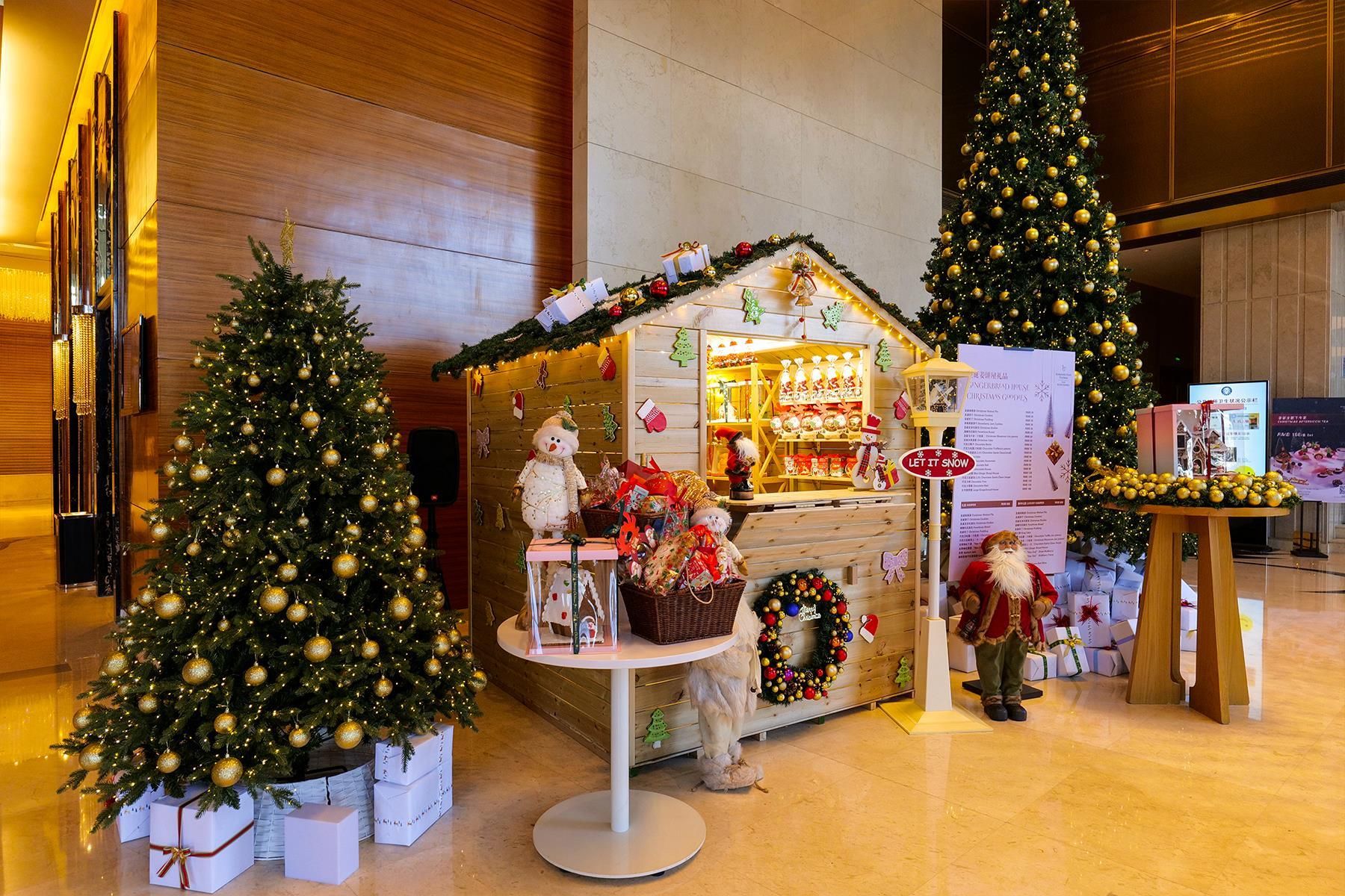 Decoración navideña con dos árboles de Navidad adornados, una pequeña tienda con un árbol de Navidad y varios artículos, y un cartel que dice 'LET IT SNOW'.