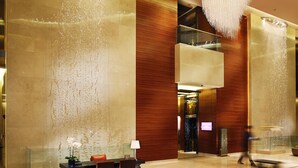 A lobby with a reception desk, chairs, a water feature, and a modern chandelier. - Kempinski Hotel Yinchuan (Yinchuan)
