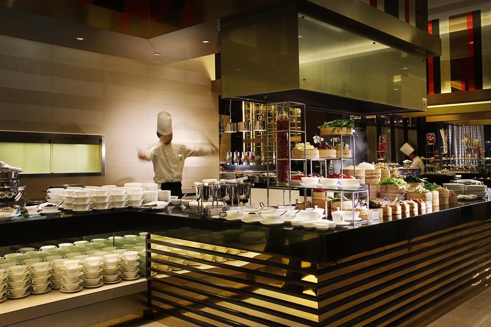A buffet setup with multiple serving stations, a chef preparing food, and a variety of dishes displayed on tiered stands.
