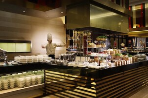 A buffet setup with multiple serving stations, a chef preparing food, and a variety of dishes displayed on tiered stands.