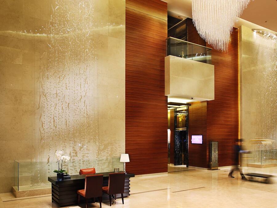 A modern lobby with a reception desk, seating area, and a large water feature.