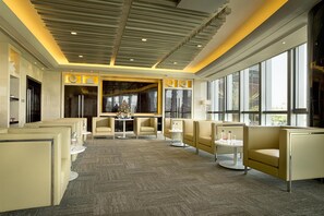 Un hall d’hôtel moderne, doté d’espaces aménagés avec des sièges, d’un comptoir d’accueil et de grandes fenêtres.