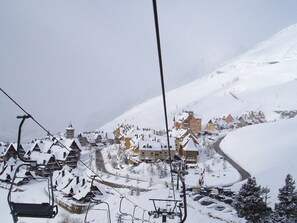 A snow-covered village with traditional buildings, a ski lift, and a winding road. - Sol Apartamentos Blanheu (Naut Aran)