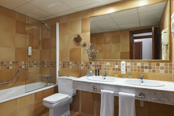 Un baño con ducha de vidrio, inodoro blanco y tocador doble con espejo.
