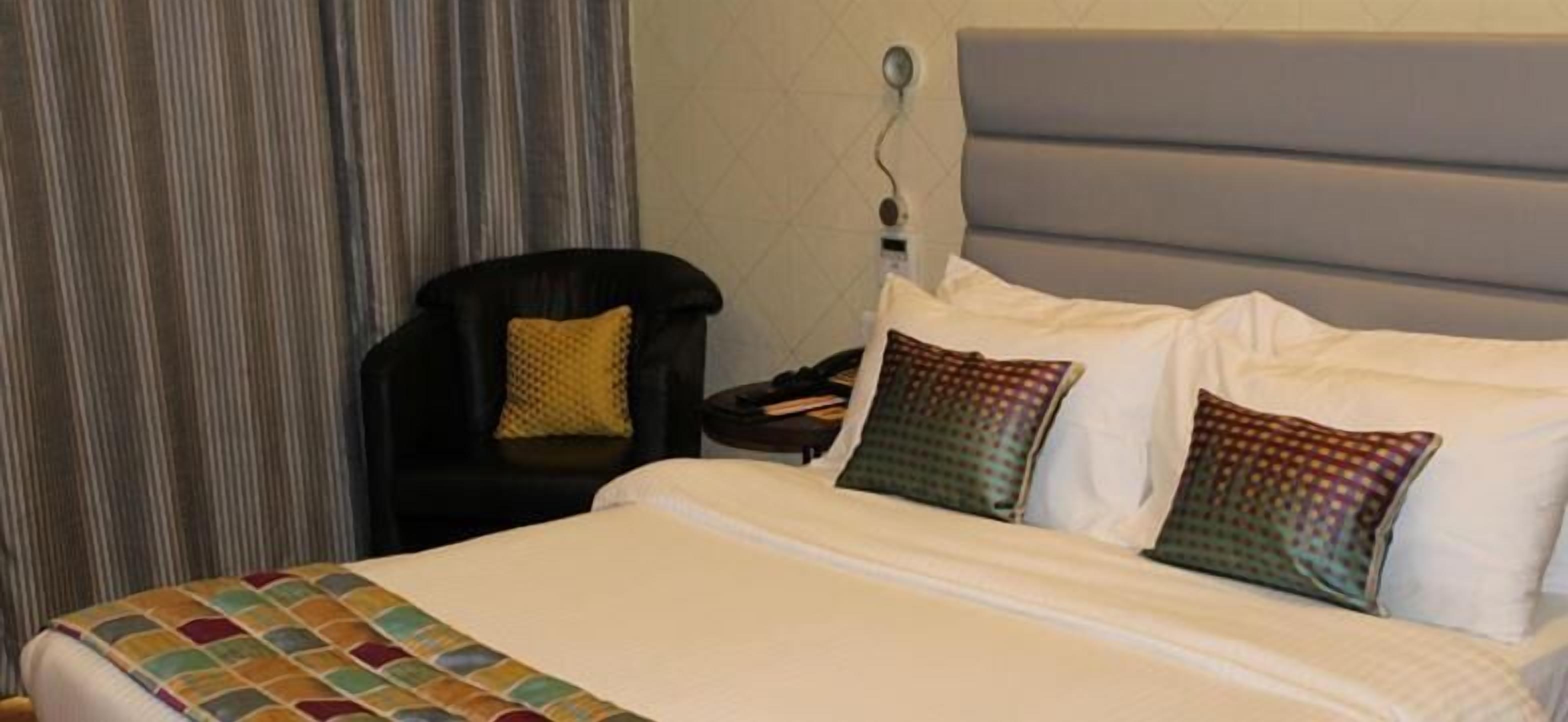 Ein Hotelzimmer mit Bett, Stuhl und Nachttisch.
