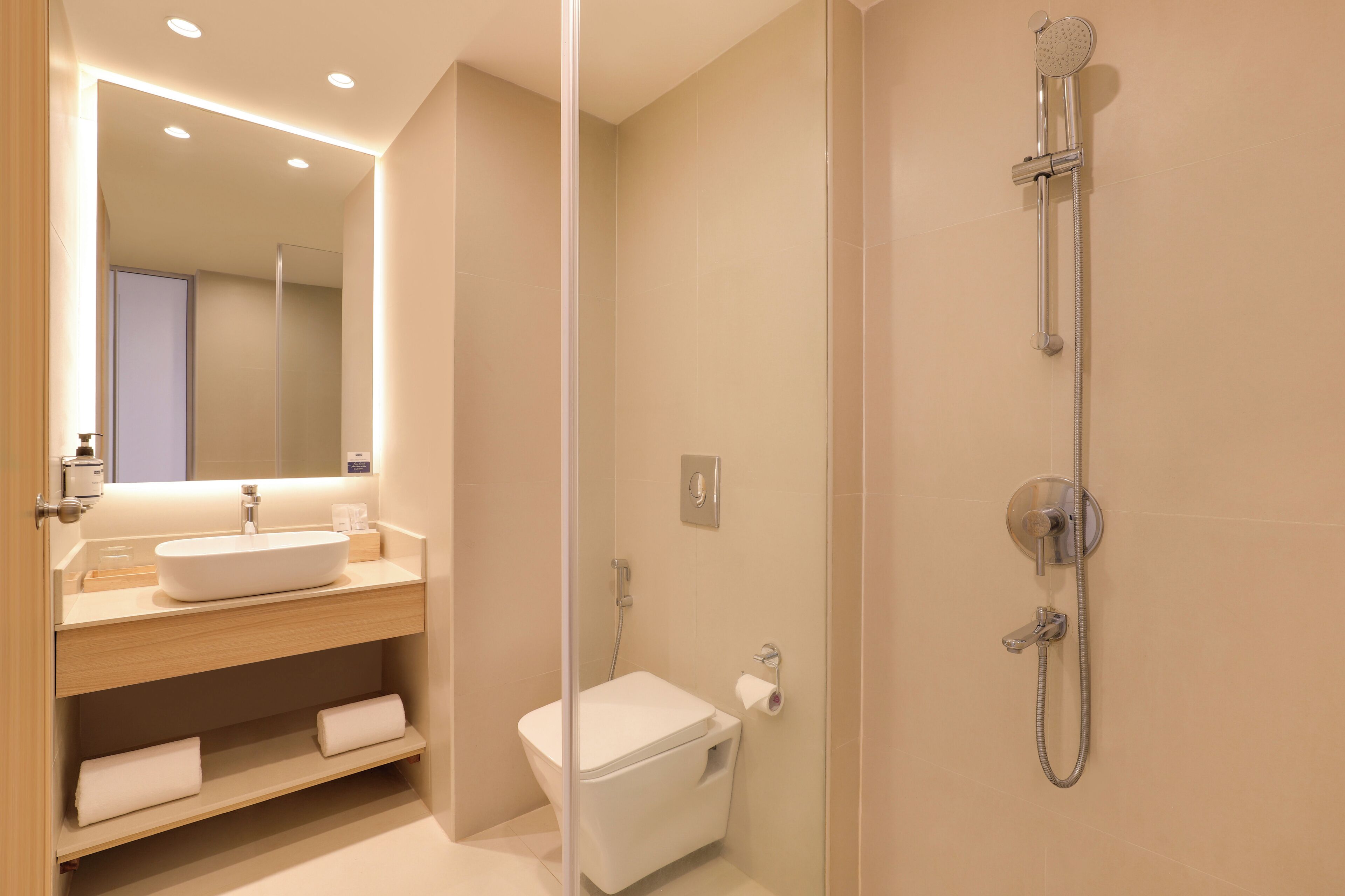 Un baño moderno con lavamanos, espejo y ducha.