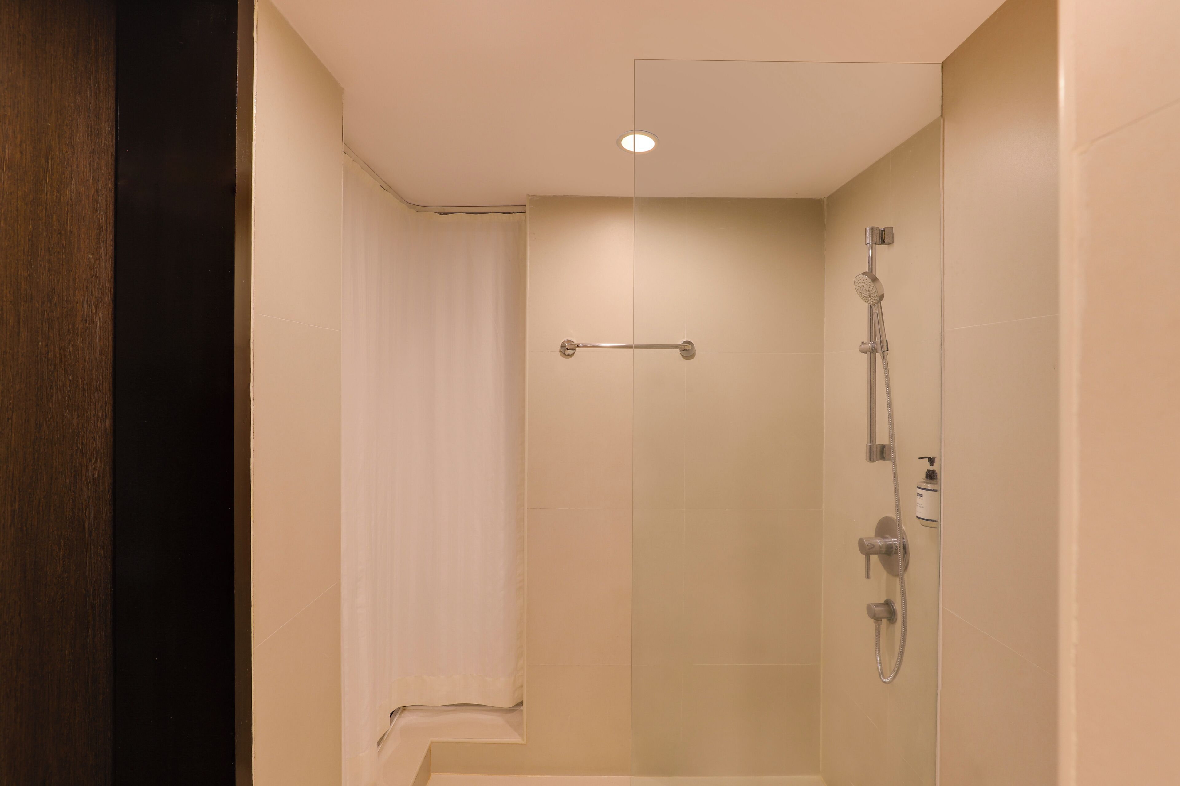 Una ducha moderna con puerta de cristal, cabezal de ducha manual y grifo monomando.