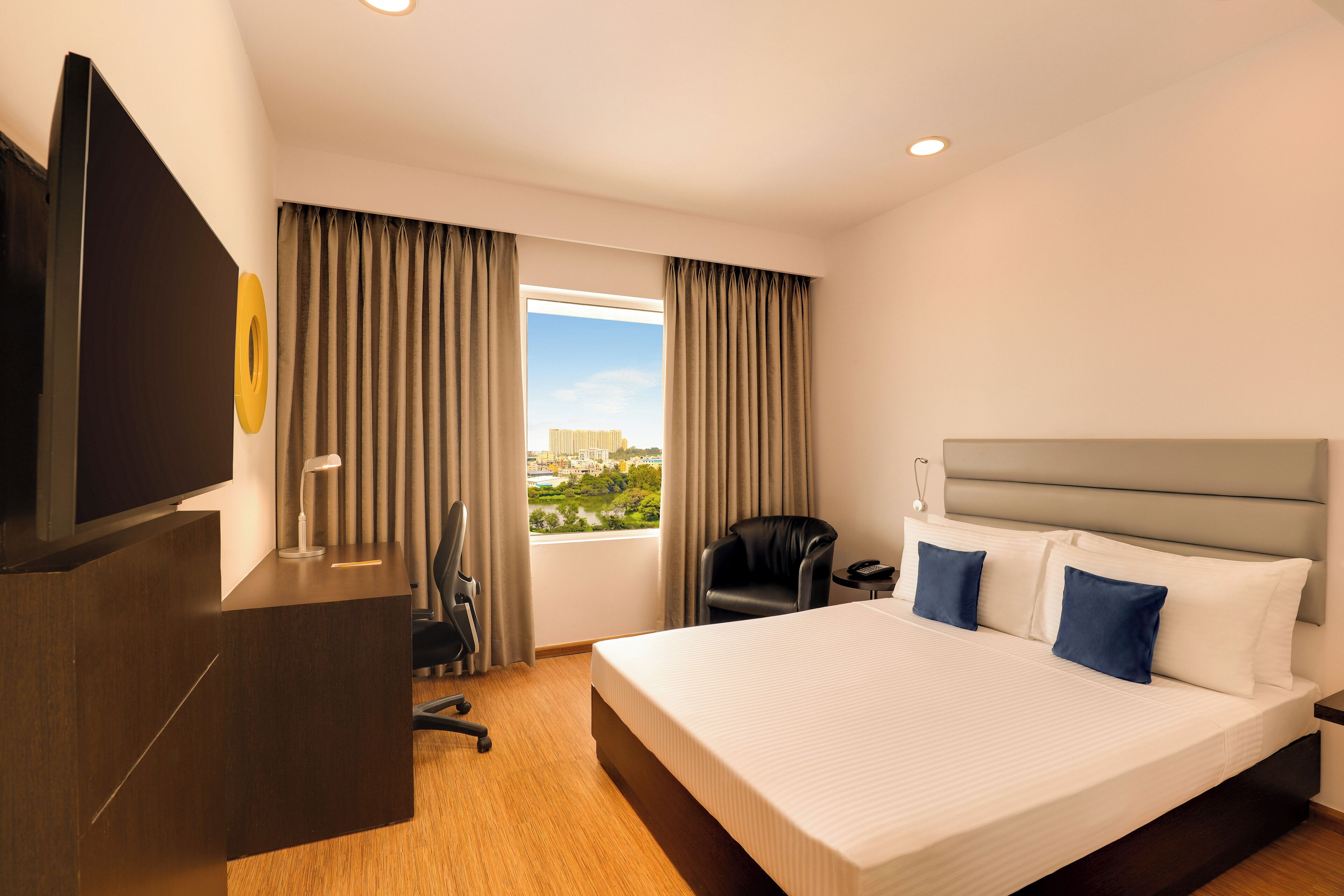 A hotel room with a large bed, a desk, a chair, and a TV.