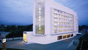 Um hotel moderno com fachada de vidro marcante, telhado plano e uma placa na entrada com a palavra "KEYS".