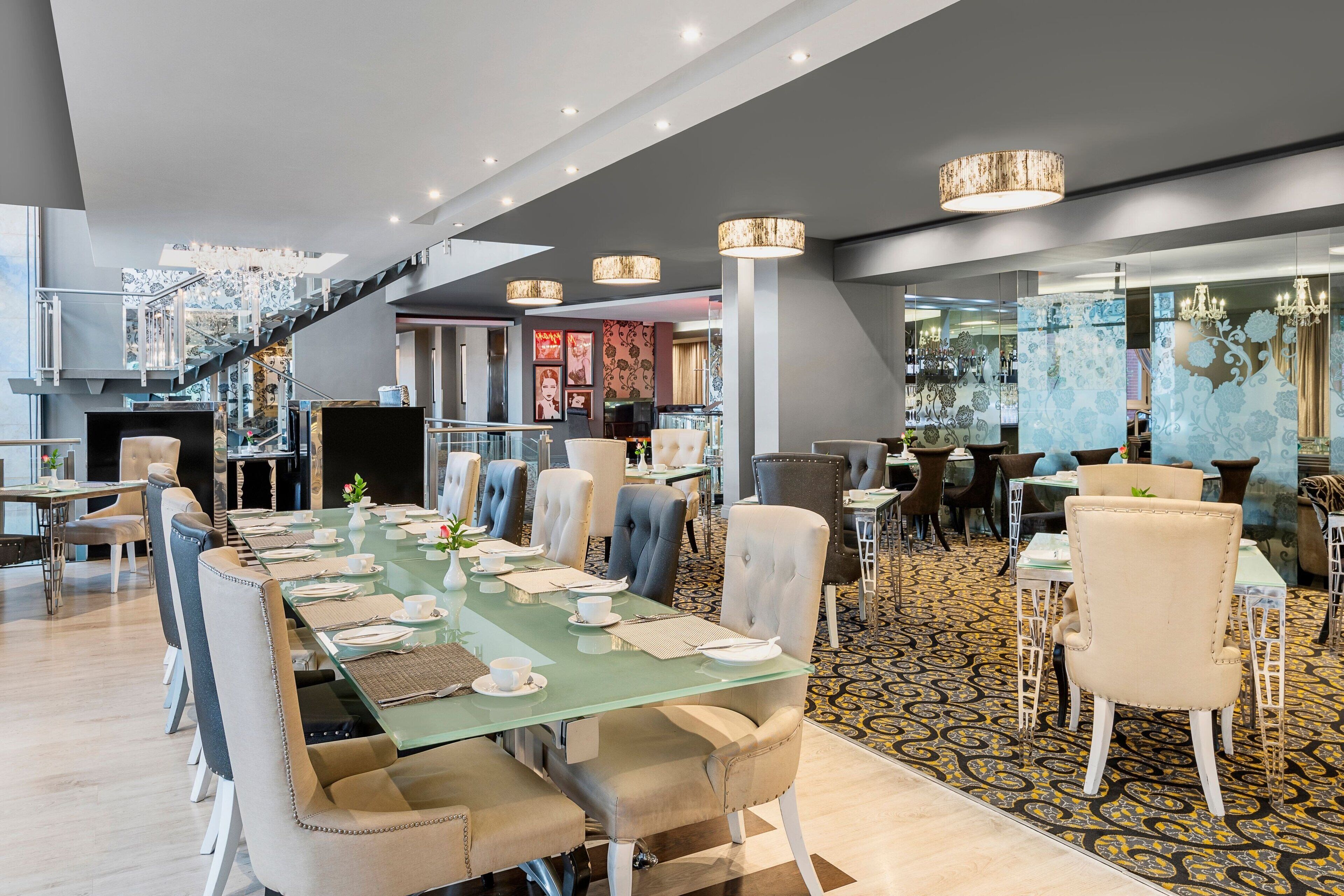Uma sala de jantar moderna com uma mesa comprida posta para refeição, rodeada por cadeiras confortáveis.