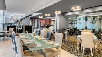 Uma sala de jantar moderna com uma mesa comprida posta para refeição, rodeada por cadeiras confortáveis.