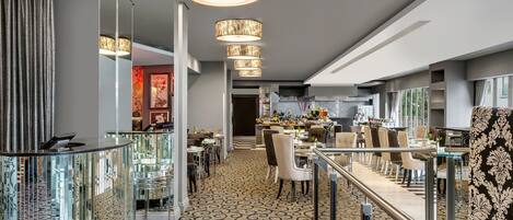 A modern hotel lobby with a central bar area, seating arrangements, and a patterned carpet.