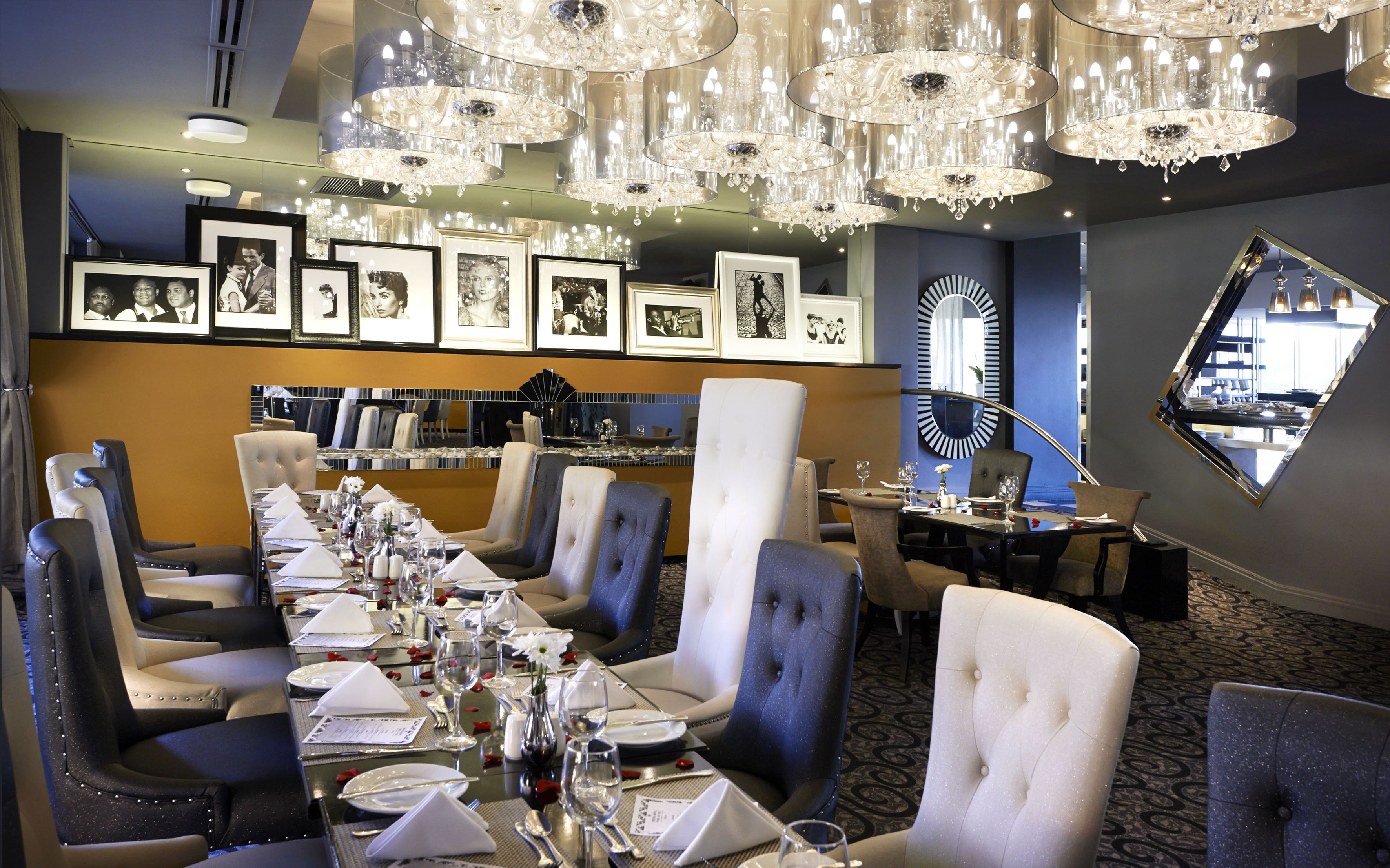 A formal dining room with a long table set for a meal, surrounded by upholstered chairs.