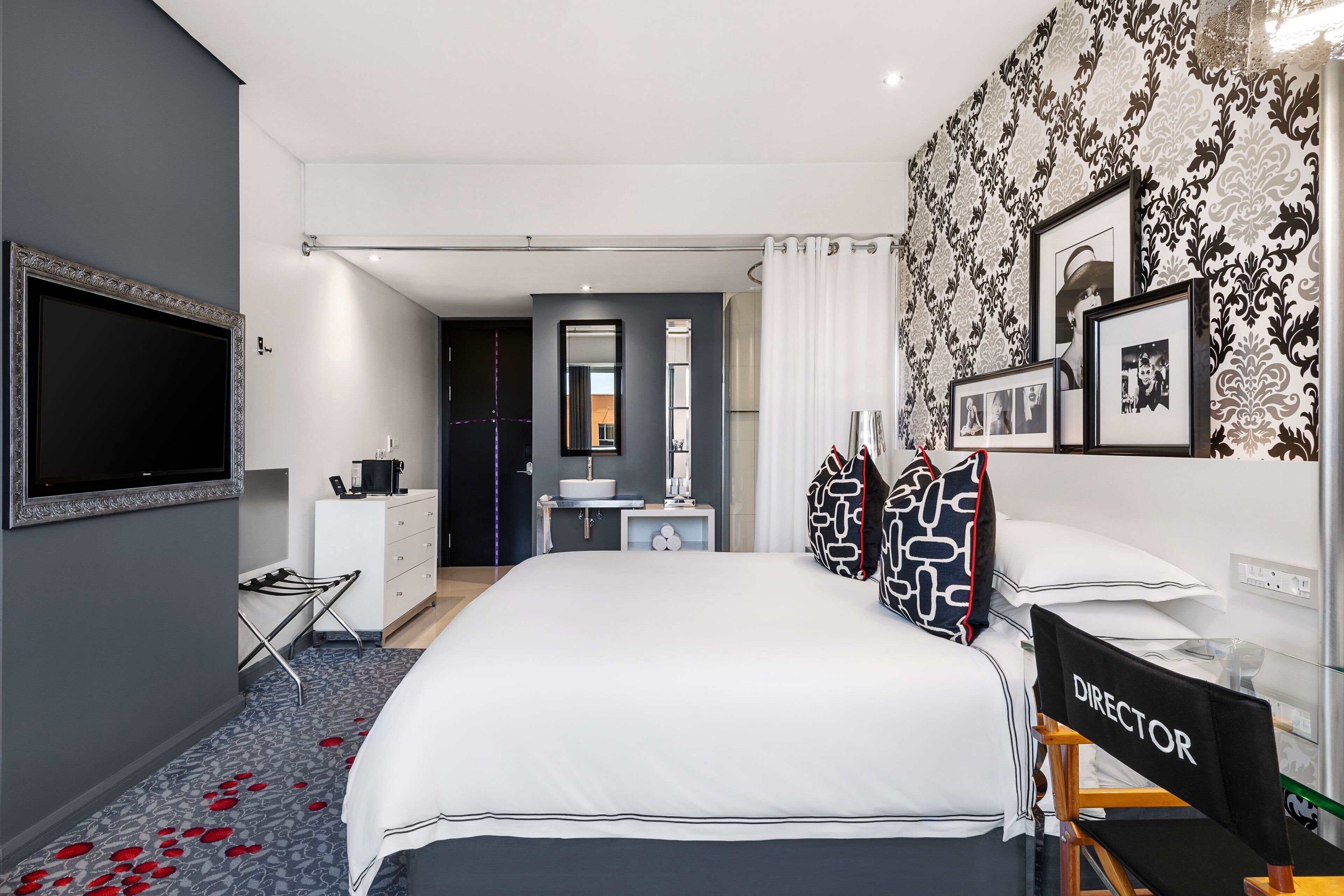 Une chambre d’hôtel moderne équipée d’un grand lit, d’un bureau, d’une coiffeuse et d’une télévision.
