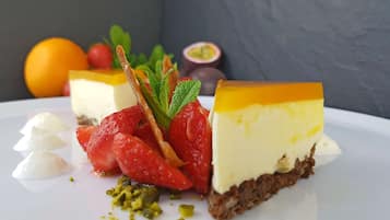 En desserttallerken med lagkage, jordbær, mynte og pistacienødder.